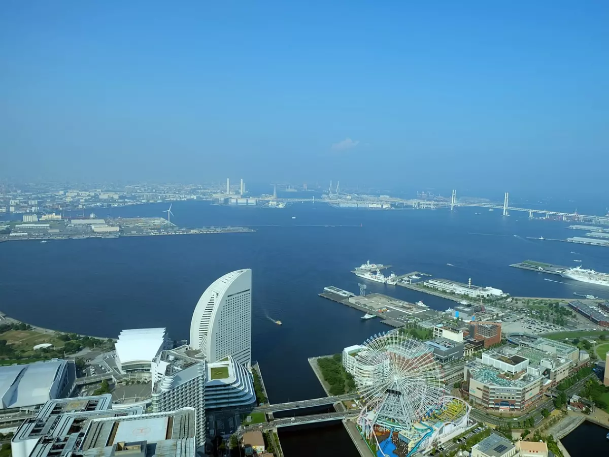 An aerial view of a cityscape with a bridge and a ferris wheel in the foreground.